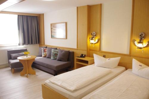 ein Hotelzimmer mit 2 Betten und einem Sofa in der Unterkunft Hotel Gasthof zum Walfisch in Klingenthal