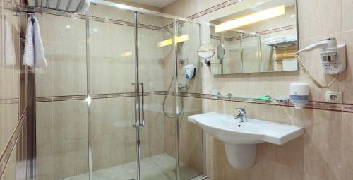 uma casa de banho com uma cabina de duche em vidro e um lavatório. em Hotel Old City by Home Hotel em Moscovo
