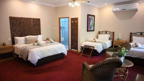 a bedroom with two beds and two chairs at LUXURY FAMILY EN-SUITE ROOM @ 4 STAR GUEST HOUSE in Middelburg