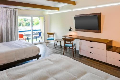 1 dormitorio con 1 cama y escritorio con TV en Golden Host Resort Sarasota, en Sarasota