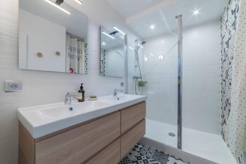 une salle de bain blanche avec un lavabo et une douche dans l'établissement le Gabut vue port, à La Rochelle