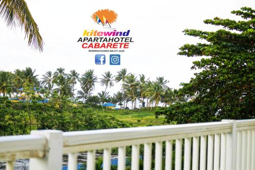 a white fence in front of a yard with palm trees at Kitewind Apartamentos Cabarete in Cabarete
