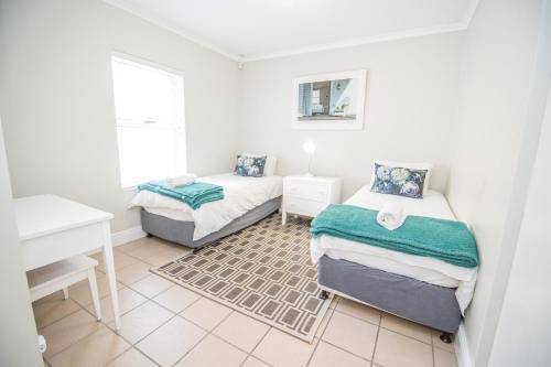 a small bedroom with two beds and a desk at Thirty River Club Villas managed by The Paper Fig House in Plettenberg Bay