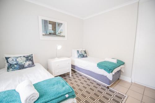 a bedroom with two beds and a mirror at Thirty River Club Villas managed by The Paper Fig House in Plettenberg Bay