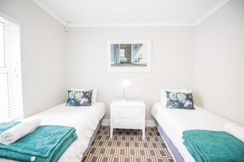 two beds in a room with white walls at Thirty River Club Villas managed by The Paper Fig House in Plettenberg Bay