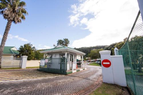 a small building with a gate and a palm tree at Thirty River Club Villas managed by The Paper Fig House in Plettenberg Bay