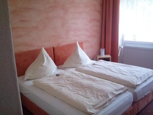 a bedroom with two beds with white sheets and a window at Hotel Garni am Bowenberg in Niederzissen
