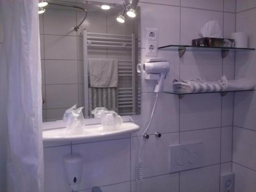a white bathroom with a sink and a mirror at Hotel Garni am Bowenberg in Niederzissen