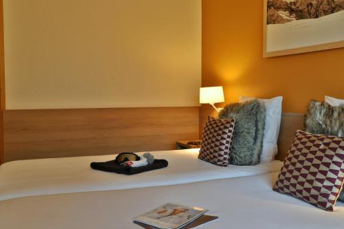 a hotel room with a bed with a book on it at SOWELL HOTELS Mont Blanc et SPA in Saint-Gervais-les-Bains
