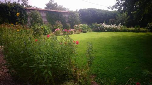 a garden with a green lawn and flowers at La Nouvelle Criqueboise in Criquebeuf-en-Caux