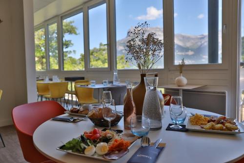 a table with two plates of food and wine glasses at SOWELL HOTELS Mont Blanc et SPA in Saint-Gervais-les-Bains