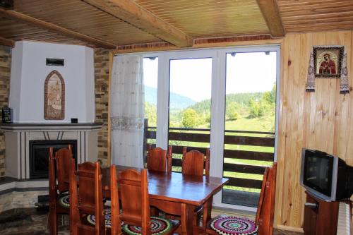 une salle à manger avec une table, des chaises et une télévision dans l'établissement Cottage "Karpatske Shale", à Yaremtche