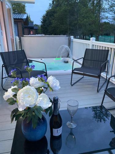 a bottle of wine and a vase with flowers on a table at Graceland Lodge with Hot Tub in Barmby on the Moor
