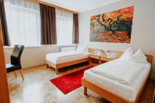 a hotel room with two beds and a red rug at Hotel am Kapuzinerplatz in Knittelfeld