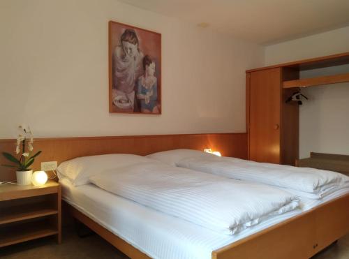 ein Schlafzimmer mit einem weißen Bett mit einem Bild an der Wand in der Unterkunft Albergo Faido in Faido