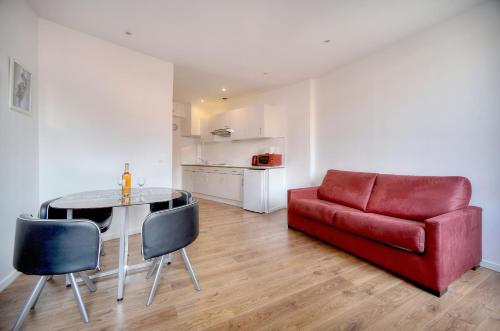 - un salon avec un canapé rouge, une table et des chaises dans l'établissement CHARMANT 2 PIECES CENTRE de CANNES - A1B209, à Cannes