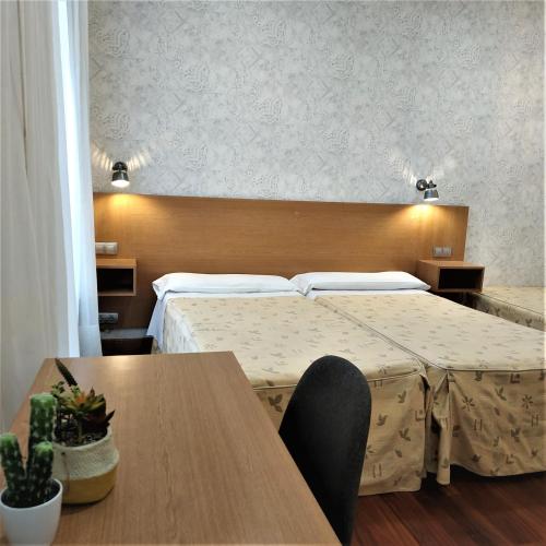 a hotel room with two beds and a table at Roquefer Bilbao by gaiarooms in Bilbao