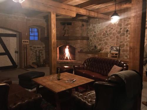 a living room with a fireplace and leather furniture at Folwark Mazurskie Legendy - Azyl dla Dorosłych in Kruklanki