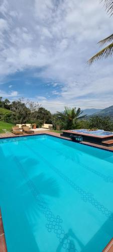 a large blue swimming pool with mountains in the background at All Natural Glamping in Copacabana