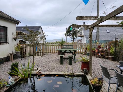 a backyard with a picnic table and a pond at Alderbank, Harrapool, IV499AE in Broadford