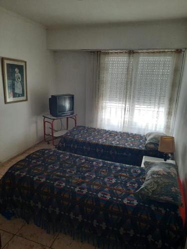 a bedroom with two beds and a tv and a window at Habitacion solo un huesped masculino hasta 25 años en casa de familia playa terminal centro wifi aire in Mar del Plata