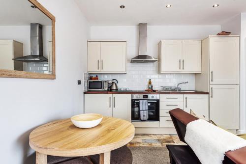a kitchen with white cabinets and a wooden table at Locket Studio - Cosy Apartment with Balcony in York