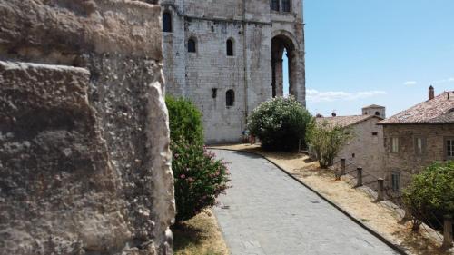 an alley in front of a stone building with flowers at Appartamento Gattapone 9 in Gubbio