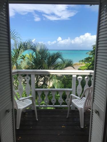 a balcony with two chairs and the ocean at Orange Hill Beach Inn in Nassau