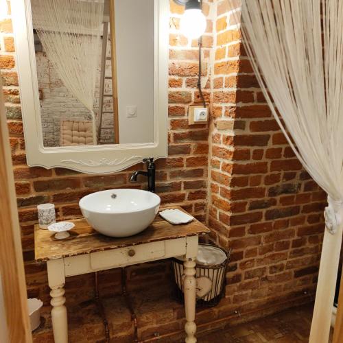 La salle de bains est pourvue d'un lavabo et d'un mur en briques. dans l'établissement Au cheval blanc, à Gommegnies