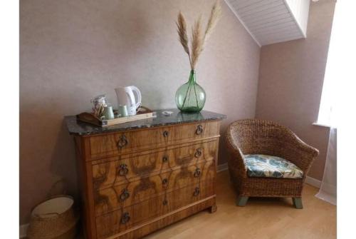 une commode avec un vase au-dessus et une chaise dans l'établissement Chambres d hôtes au Domaine de Robert, à Fleurie