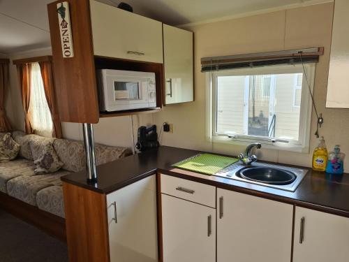 a small kitchen with a sink and a couch at 8 Berth on Coastfields Ingoldmells (Vacation) in Ingoldmells