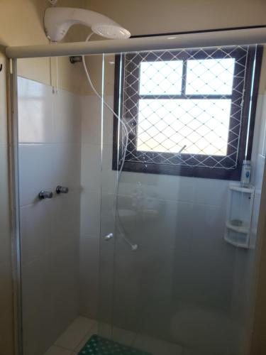 a bathroom with a glass shower with a window at Apartamento Flor de Canela in Canela