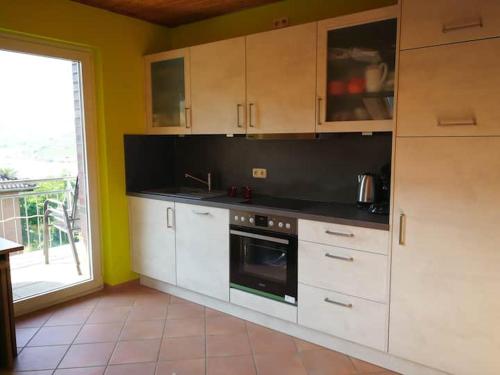 a kitchen with white cabinets and a large window at Wunderschöne Aussicht garantiert in Trechtingshausen