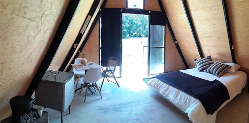 a bedroom with a bed and a table in a room at Glamping Nool in Río Blanco