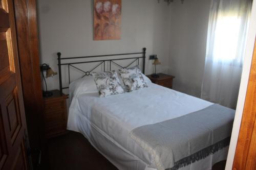 1 dormitorio con 1 cama con sábanas y almohadas blancas en Les Casines, en Luanco