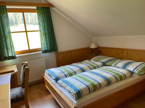 Cette chambre comprend un grand lit et une fenêtre. dans l'établissement Ferienhaus Alpenblick, à Krakauschatten