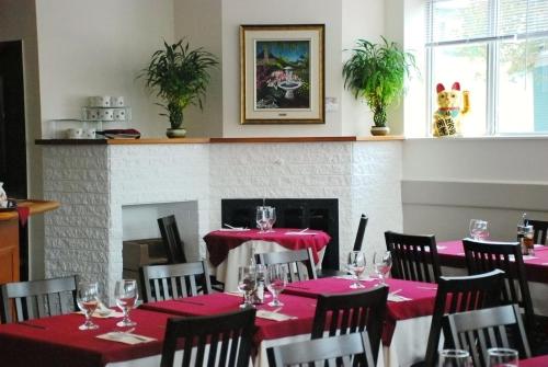 a dining room with red tables and chairs and a fireplace at Auberge du Grand Lac in Magog-Orford
