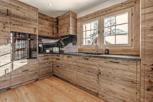 eine Küche mit Holzwänden, einem Waschbecken und einem Fenster in der Unterkunft Alpslodge - Napa in Arosa