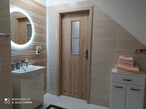 a bathroom with a sink and a wooden door at Rodinný penzion U Hafana a U Hospůdky in Řeka