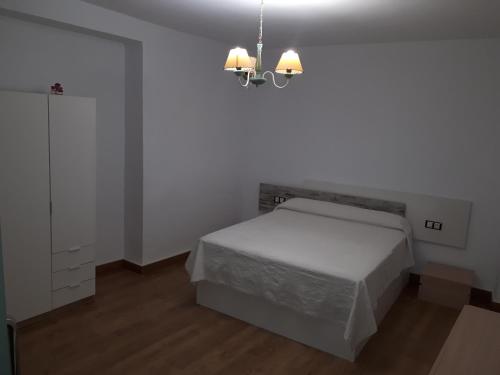 - une chambre blanche avec un lit et un lustre dans l'établissement Casa Sculpture, à Bogarra