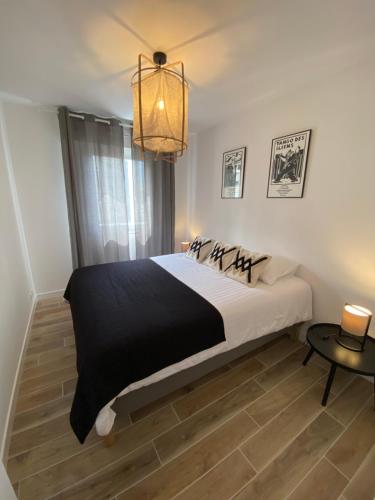 une chambre avec un grand lit et un lustre dans l'établissement LAPEROUSE 2B coeur de ville et plage à pied pour 4 - parking privé gratuit, à Concarneau