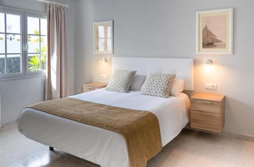 a bedroom with a large white bed and a window at Villas Maribel Pocillos in Puerto del Carmen