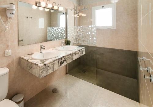 ein Bad mit 2 Waschbecken, einer Dusche und einem Spiegel in der Unterkunft Villas Maribel Pocillos in Puerto del Carmen
