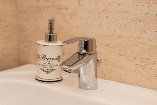 un lavandino in bagno con rubinetto e una bottiglia di sapone di K'RAMAN a Râmnicu Vâlcea