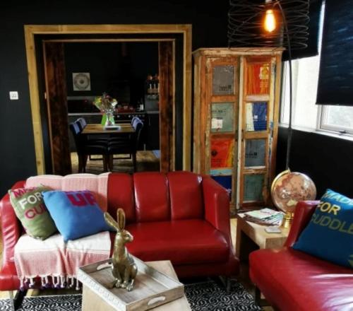 sala de estar con sofá rojo y mesa en Drumdelgie Cottages, en Huntly