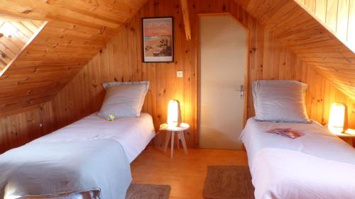 2 camas en una habitación con paredes de madera en Penthièvre - Maison 6 pers avec Jacuzzi, proche des plages, en Saint-Pierre-Quiberon