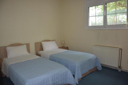 two beds in a white room with a window at Spacious Apartment at Ioannina, Anatoli in Anatolí