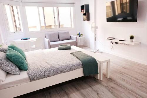 biała sypialnia z łóżkiem i krzesłem w obiekcie Precioso apartamento a 150 metros de la Playa w mieście Las Palmas de Gran Canaria