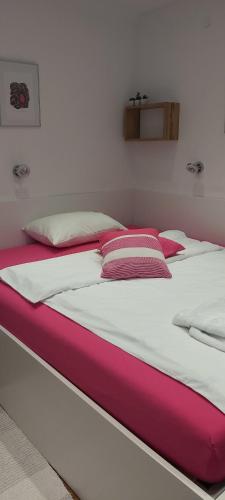 ein großes Bett mit rosa und weißer Bettwäsche und Kissen in der Unterkunft Apartment EMA in Ljubljana