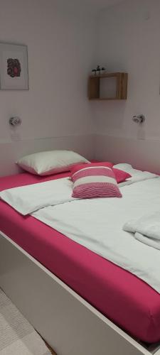 a large bed with pink and white sheets and pillows at Apartment EMA in Ljubljana